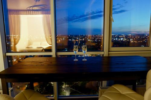 two wine glasses on a wooden table in front of a window at Апартаменты в Одессе in Odesa