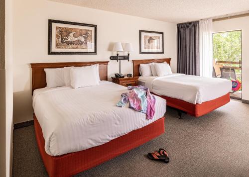 two beds in a hotel room with shoes on the floor at Lake Powell Resort in Page