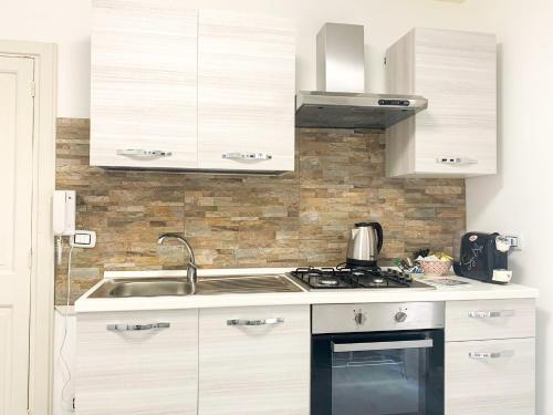 una cucina bianca con lavandino e piano cottura di RockSea Apartments a Cefalù