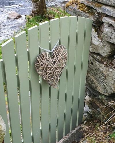 a green fence with a heart hanging on it at Smithy Cottage in Kirkmichael
