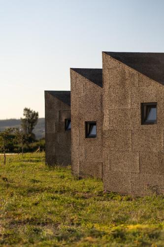two stone buildings on a field with grass at Gavião Nature Village in Gavião