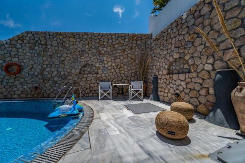 a patio with a swimming pool next to a stone wall at Stavros Villas in Karterados