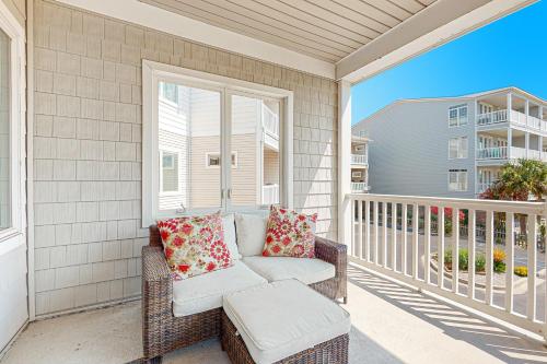 um sofá de vime sentado em uma varanda com uma janela em Cool Corner em Folly Beach