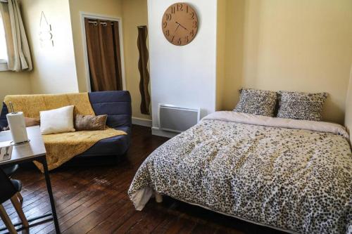 a bedroom with a bed and a couch and a clock at Grand studio in Boulogne-sur-Mer