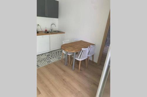 une cuisine avec une table en bois et des armoires blanches dans l'établissement Appartement neuf 4-6 personnes en bord de Mer, à Nice