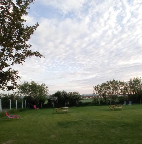 dos bancos en un campo con un cielo nublado en La ferme du guindal en Marquise