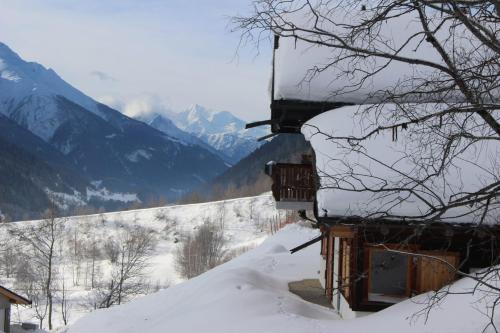 a building covered in snow with mountains in the background at Chalet La Neuf in Blitzingen