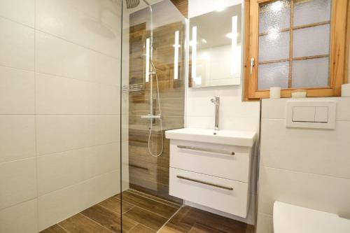 a white bathroom with a sink and a shower at Chalet La Neuf in Blitzingen