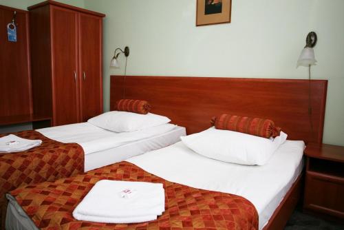 two beds in a hotel room with white towels on them at Hotel Arkadia in Legnica