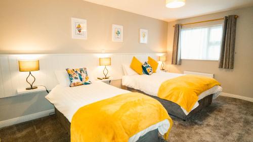 two beds in a room with yellow sheets at Sraid Eoin House in Dingle