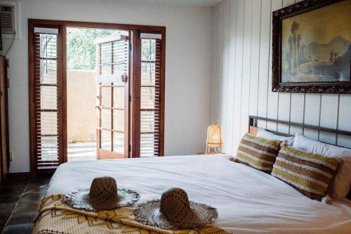 Un dormitorio con una cama con dos sombreros. en The Good House- Hot Spring Hideaway, en Desert Hot Springs