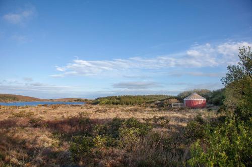 a red barn in a field next to a lake at Lough Mardal Lodge in Donegal
