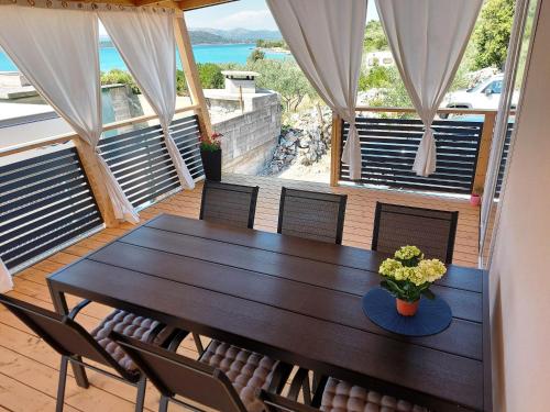 a table and chairs on a deck with a view of the ocean at Mobile homes Charly in Tisno