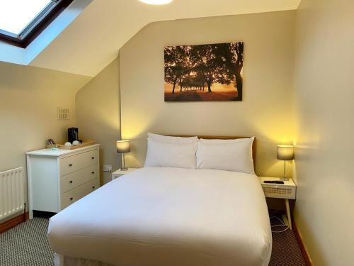 a bedroom with a large white bed and a dresser at Feeney's Audubon Lodge in Galway