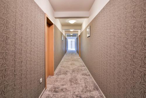 a hallway with brown walls and a long aisle at LH Parkhotel Hluboka Nad Vltavou Congress & Wellness in Hluboká nad Vltavou