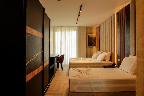 シェンジンにあるRozafa Blu Hotelのベッド2台とデスクが備わるホテルルームです。