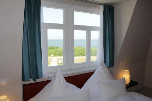 ein Schlafzimmer mit einem Bett und einem großen Fenster in der Unterkunft Pension Strandschloss Arielle in Börgerende-Rethwisch