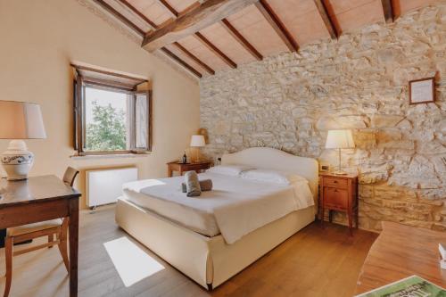 1 dormitorio con cama y pared de piedra en Terenzi Hospitality & Wine, en Scansano