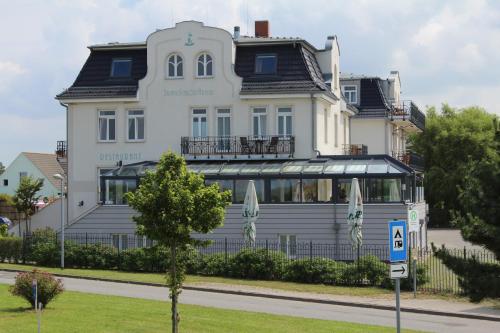 a large white building with a sign in front of it at Pension Strandschloss Arielle in Börgerende-Rethwisch