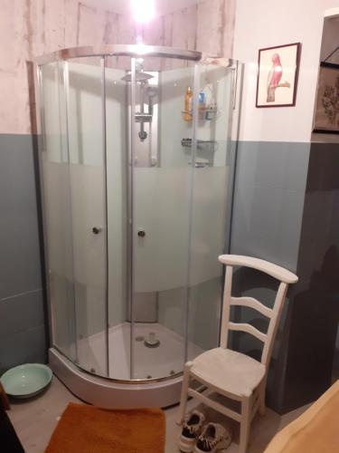 a shower with a glass enclosure next to a chair at Maison authentique en pierre apparente en montagne dans le c antal in Thiézac