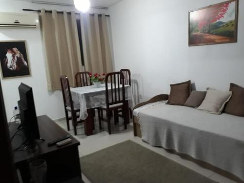 een woonkamer met een bed en een tafel met een tv bij Recanto chalenger in Campos dos Goytacazes