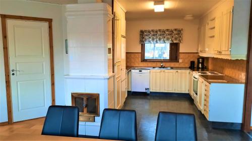 a kitchen with white cabinets and blue chairs in it at Camp Alta Kiruna in Kiruna