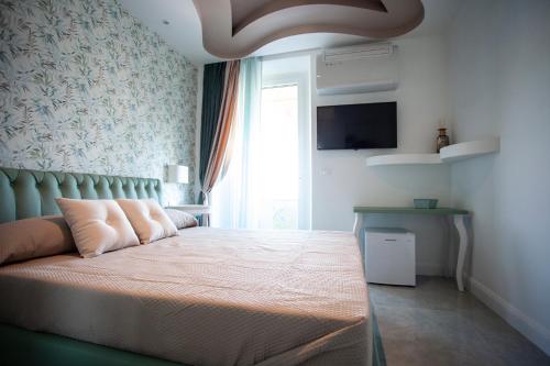 a bedroom with a bed and a window and a television at Cavalieri D'Oro Luxury House in Anzio