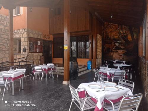 a patio area with tables, chairs, and umbrellas at Hostal el Hayedo in Cantalojas