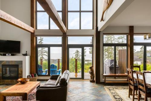 a living room with large windows and a fireplace at Black Rock Ridge in Ucluelet