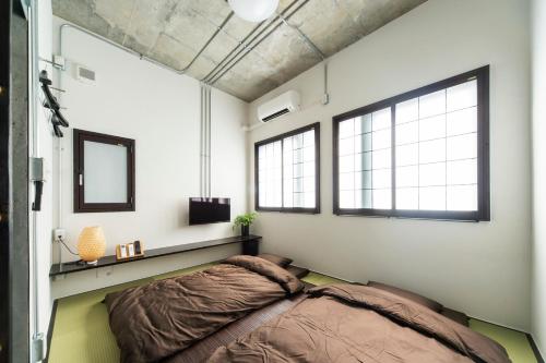 a bedroom with a bed and two windows at Oyado danran 団欒 in Tokyo