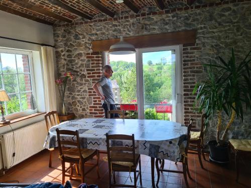 una mujer parada frente a una mesa en una habitación en Maison de campagne avec superbe vue panoramique!, en Bousignies-sur-Roc