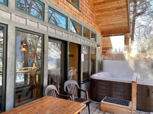 a porch with a hot tub and a table and chairs at River's Edge Resort in Winthrop