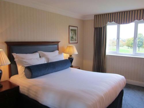 a hotel room with a bed with a blue pillow on it at Windmill Village Hotel, Golf Club & Spa, BW Signature Collection in Coventry