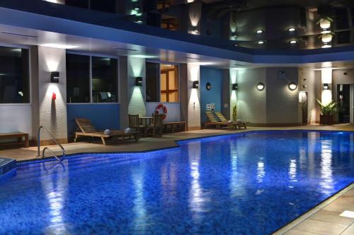 a large swimming pool in a hotel at night at Windmill Village Hotel, Golf Club & Spa, BW Signature Collection in Coventry