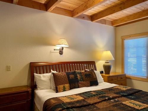 a bedroom with a bed and a lamp and a window at River's Edge Resort in Winthrop