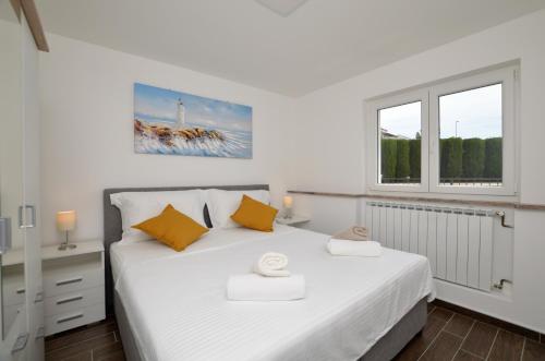 a bedroom with a white bed and two windows at Villa Sofia in Martinšćica