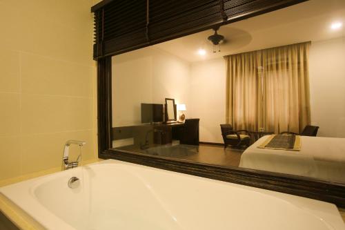 a bathroom with a large mirror over a bath tub at Chu Hotel in Da Nang