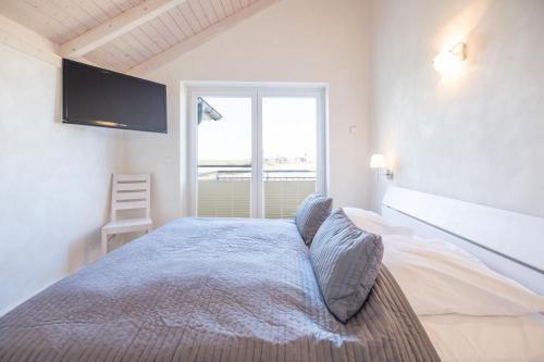 um quarto com uma cama e uma televisão na parede em Ferienhaus Nordspitze em Dagebüll