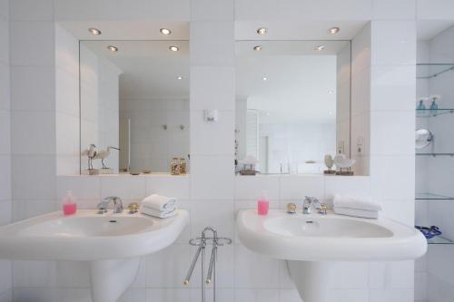 ein weißes Badezimmer mit 2 Waschbecken und einem Spiegel in der Unterkunft Wohlfühloase Büttjebüll in Bordelum