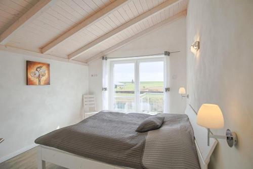 a white bedroom with a bed and a window at Ferienhaus Lachmöwe in Dagebüll