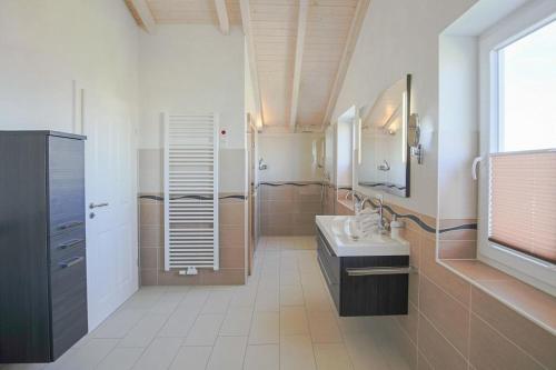 uma grande casa de banho com um lavatório e um chuveiro em Ferienhaus Silbermöwe em Dagebüll