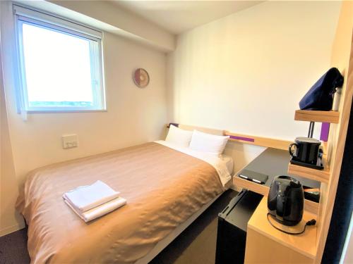 a bedroom with a bed and a desk and a window at Center Hotel Narita2 R51 in Narita