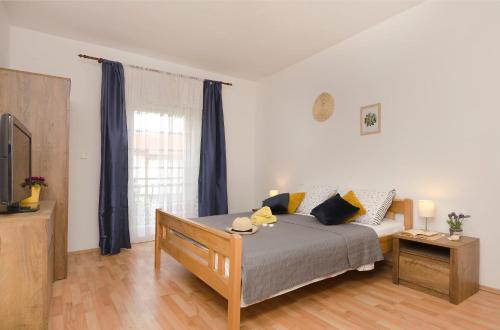 a bedroom with a bed with blue curtains and a tv at Apartments Ivana in Murter