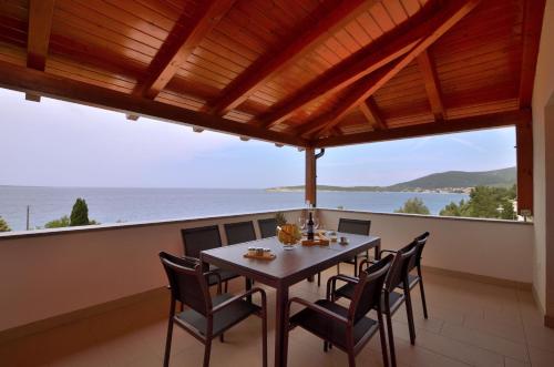 uma mesa e cadeiras numa varanda com vista para o oceano em Apartments Villa Sofia em Martinšćica
