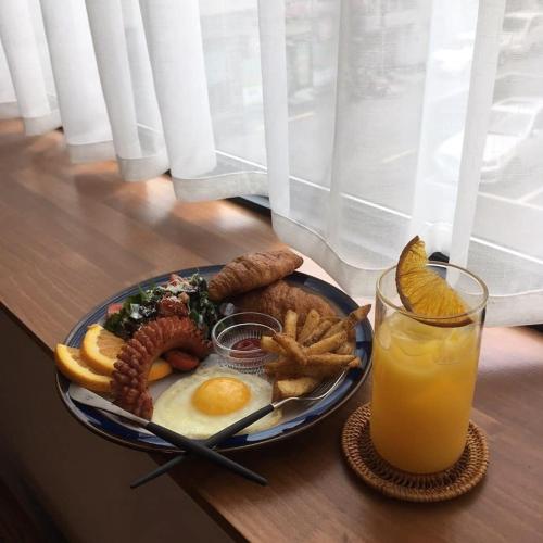 un piatto di prodotti per la colazione e un bicchiere di succo d'arancia di Brown-Dot Hotel Choeup a Busan
