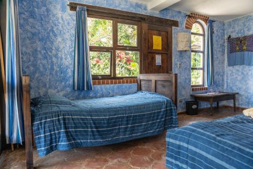 a blue bedroom with two beds and a window at La Iguana Perdida in Santa Cruz La Laguna