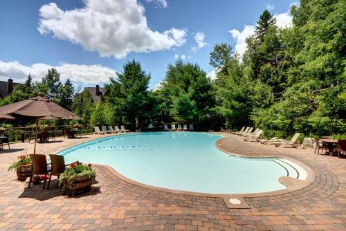 une grande piscine avec des chaises et des tables dans l'établissement Le Plateau by Tremblant Vacations, à Mont-Tremblant