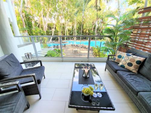 a living room with a couch and a table and a pool at Palm Cove Beach Apartment in Palm Cove
