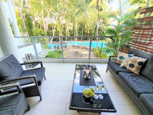 パーム・コーブにあるPalm Cove Beach Apartmentのソファとテーブルとプールのあるリビングルーム