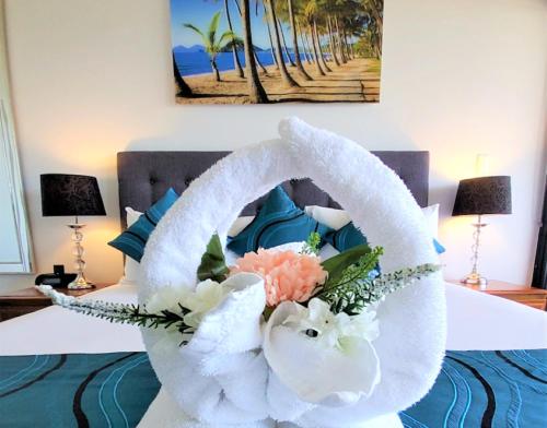 uma cama com toalhas brancas e flores em Palm Cove Beach Apartment em Palm Cove